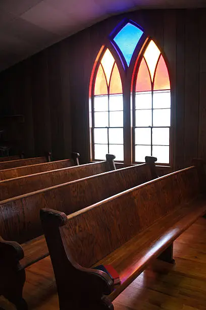 This arched, stained glass window casts a soft glow on the wooden pews in this central Iowa country church. 