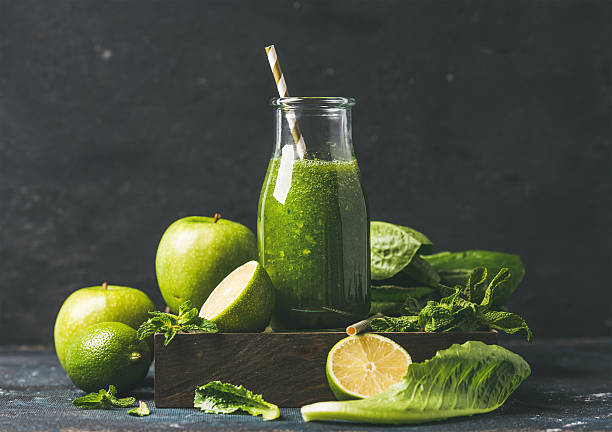 Green smoothie in glass bottle with apple, romaine lettuce, lime stock photo