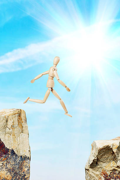 istock Man jumping from the one rock to another over precipice 629027580