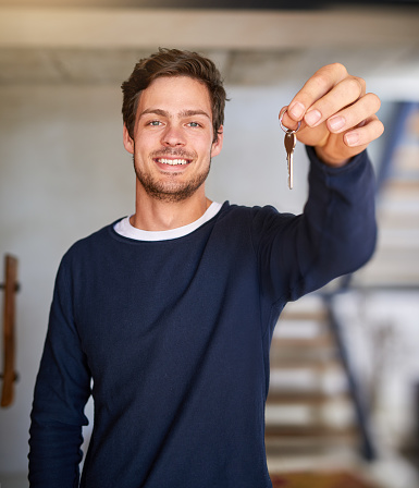 Portrait of a happy young man holding up the key to his new home