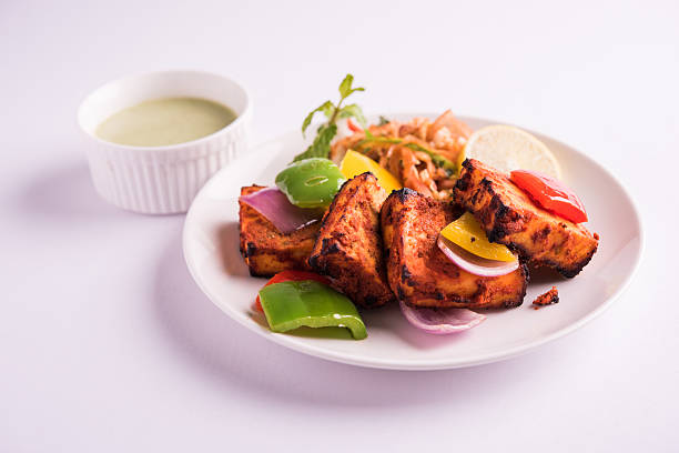 chilli paneer tikka or paneer kabab Paneer Tikka or chilli paneer Kabab - Tandoori Indian cheese skewers, served in white plate with colourful capsicum and onion, with green sauce Paneer Tikka stock pictures, royalty-free photos & images