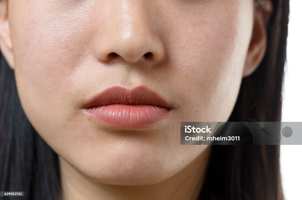 View of the lower facial features of a woman Cropped view of the lower facial features and closed mouth of a young Chinese woman with a serene calm expression and long dark hair Close-up Stock Photo