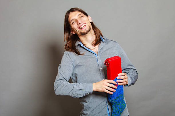 istock Guy putting wrapped gift in knitted christmas sock 629061938