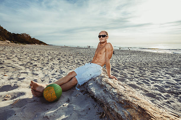 hombre delgado en pantalones cortos en una playa - men refreshment male summer fotografías e imágenes de stock