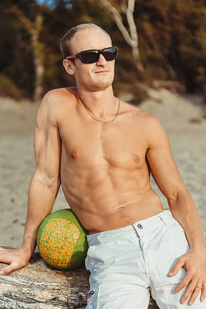 hombre delgado en pantalones cortos en una playa - men refreshment male summer fotografías e imágenes de stock