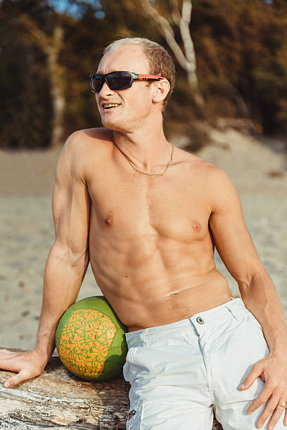 hombre delgado en pantalones cortos en una playa - men refreshment male summer fotografías e imágenes de stock