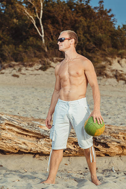 hombre delgado en pantalones cortos en una playa - men refreshment male summer fotografías e imágenes de stock