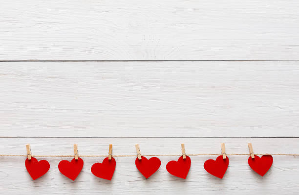 Valentine day background, paper hearts border on wood, copy space Valentine background with red paper hearts row border on clothespins on white rustic wood planks. Happy lovers day card mockup, copy space clothespin wood stock pictures, royalty-free photos & images