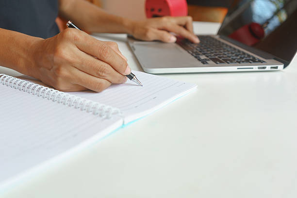 istock Woman using laptop and writing report on a notebook 629076604