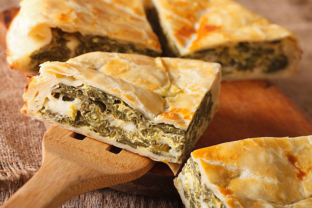 Greek pie with spinach and cheese spanakopita close-up. horizontal Greek pie with spinach and cheese spanakopita close-up on a table. horizontal spanakopita stock pictures, royalty-free photos & images