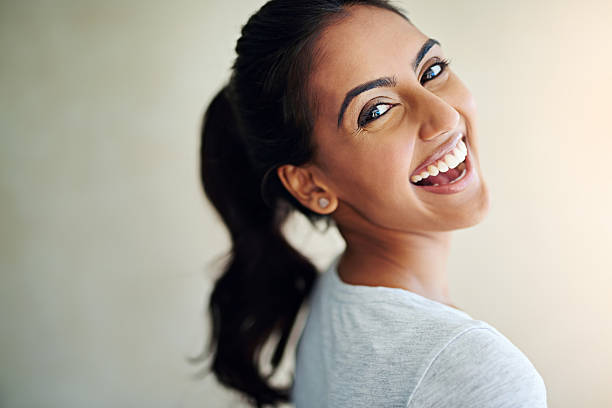 Feeling fantastic and it shows Studio portrait of an attractive and happy young woman looking back over her shoulder Toothy Smile stock pictures, royalty-free photos & images