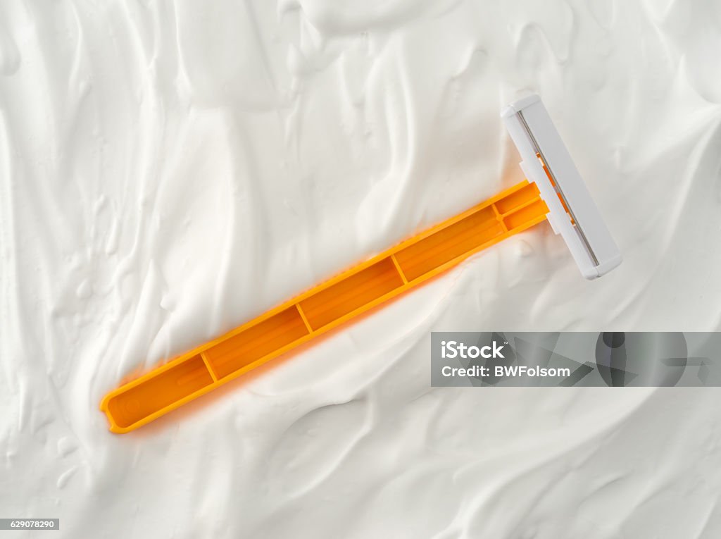 Generic disposable razor on shaving foam Top view of a generic disposable shaving razor that has fallen into shaving foam. No People Stock Photo