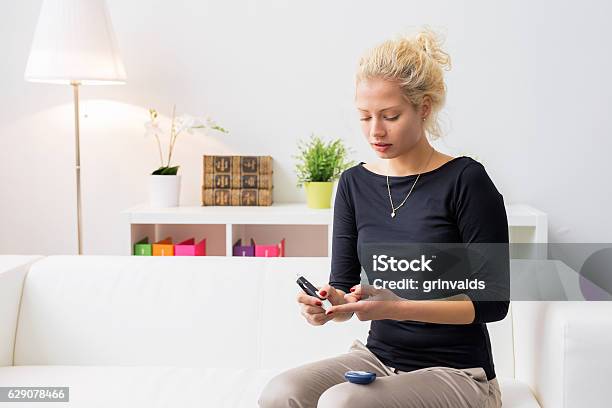 Woman Sitting On Couch And Using Diabetes Needle Stock Photo - Download Image Now - Diabetes, Organization, Blood Sugar Test