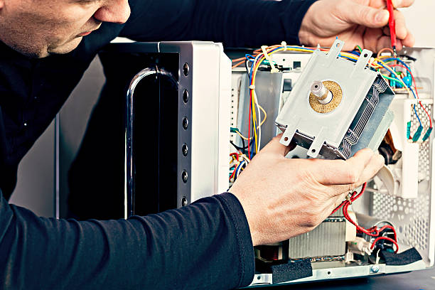 Serviceman electrician repairs a magnetron in the microwave