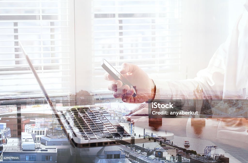 hands with smartphone, mobile application or checking email double exposure of hands of business man using smartphone in the office, London cityscape On The Move Stock Photo