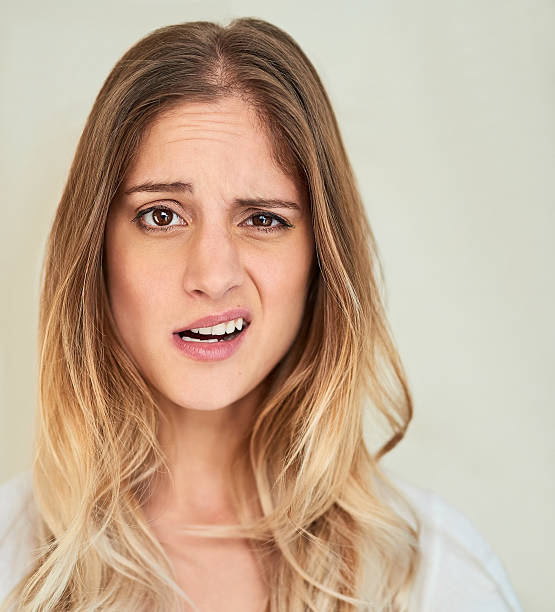 What are you talking about? Portrait of a young woman making a face in studio confused face stock pictures, royalty-free photos & images