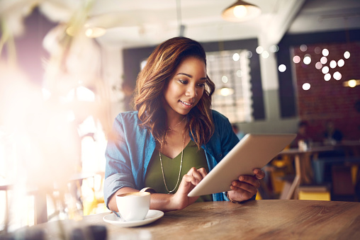 Cropped shot of an attractive young woman using a digital tablet in a cafe