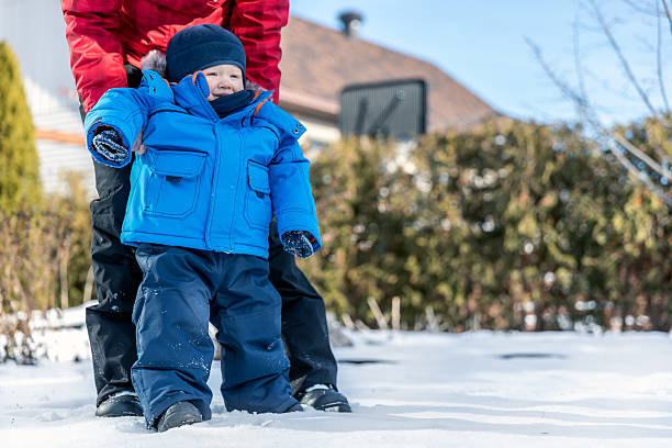 istock Baby Learning to Walk in Snow with Mom 629128190
