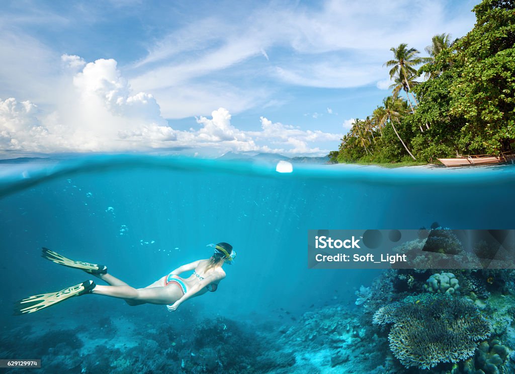 Woman snorkeling in tropical waters in near of exotic island Woman swims around a coral reef surrounded by a multitude of fish. Philippines Stock Photo