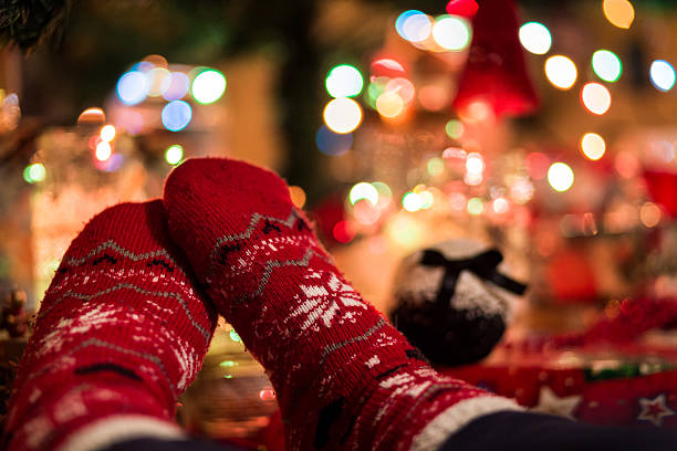 istock Feet wearing red Christmas socks beneath illuminated Christmas Tree 629145476