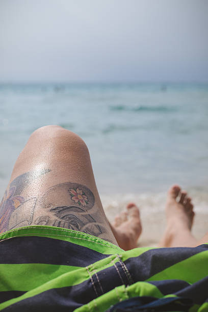 Scater with a big tatoo sitting on the beach.