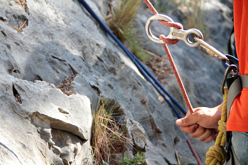 Close-up of rock climber arm and knot rope. Outdoor climbing concept.