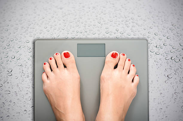 istock Help to lose kilograms with woman feet stepping on scale 629155676