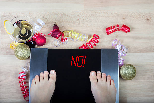 escamas con cartel de "¡no!" rodeadas de adornos navideños y alcohol. - holiday healthy lifestyle weight christmas fotografías e imágenes de stock