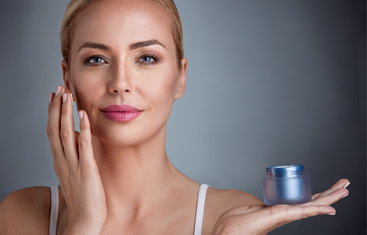 Beautiful nourished woman holding cream for her skin