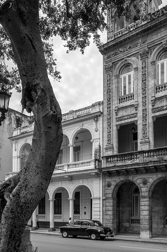 Havana, Cuba - October 11, 2016: Spanish Colonial building on Prado Boulevard in Old Havana, Cuba. Prado Boulevard is one of the major streets in downtown Havana, leading from Malecon shore line to Capitolio Parliament building. Typical scene all around old Havana, where ever you see old buildings . Variety of colours and styles. Beauty of old architecture neglected over many years with out upkeep. People walking on the sidewalk, old cars parked on the street.