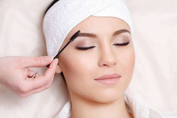 istock Beautiful young woman gets eyebrow correction procedure 629183388