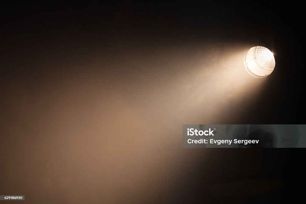 Ray of scenic spot light over dark Ray of scenic spot light over dark background, stage illumination equipment Spot Lit Stock Photo
