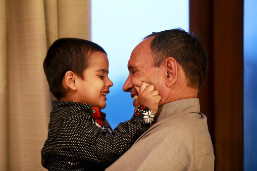 Little child loving portrait with his grandfather in hotel room on a vacation at night.