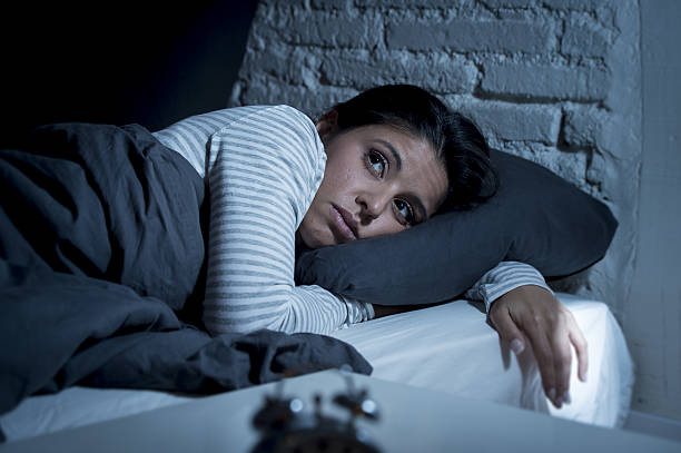 woman in bed late night trying to sleep suffering insomnia stock photo
