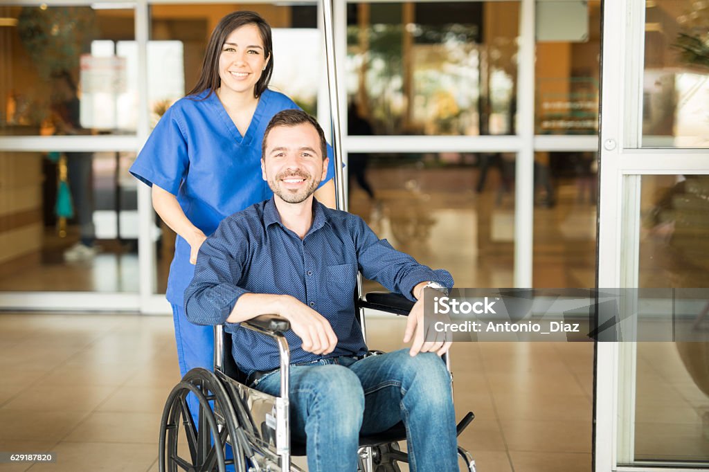 Recovered patient leaving the hospital Portrait of a young Hispanic patient leaving the hospital in a wheelchair after a full recovery Hospital Stock Photo