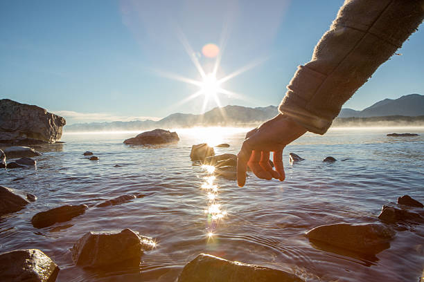 istock Finger touches surface of mountain lake 629189334