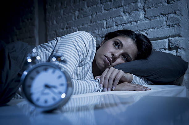 woman in bed late night trying to sleep suffering insomnia - insomnia imagens e fotografias de stock