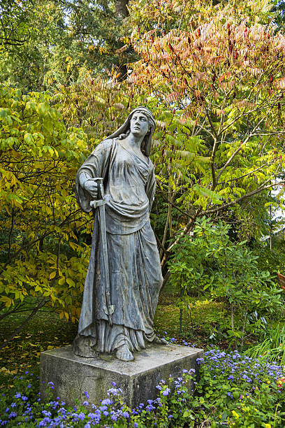 Vienna, Austria - December 20, 2024: Weathered stone statue of a seated robed figure in a cemetery, with its head broken off, symbolizing decay and the passage of time.