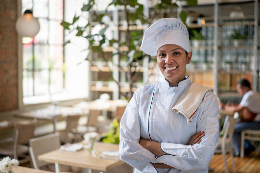 Happy female Chef working at a restaurant and looking at the camera smiling