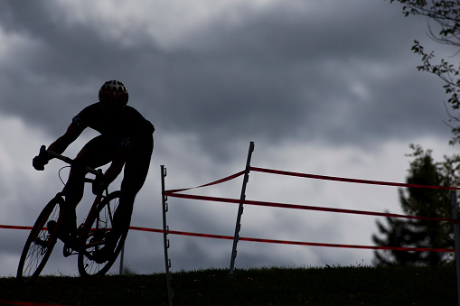A man competes in a cyclo-cross bicycle race at the end of the day.