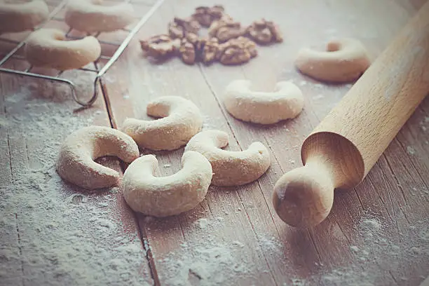 Crescent vanilla cookies, with some flour, walnuts and rolling pin on a wooden table