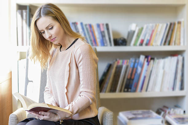 istock beautiful young women reding book in office 629215012