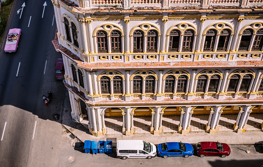 Havana, Cuba - October 8, 2016: Bird eye view of corner of Prado Boulevard and side street. Located in centre of Old Havana, this area is rich with old colonial architecture. Vintage facade in full glow on afternoon sun, people on the streets. Pink vintage American convertible with tourists passing down Prado.