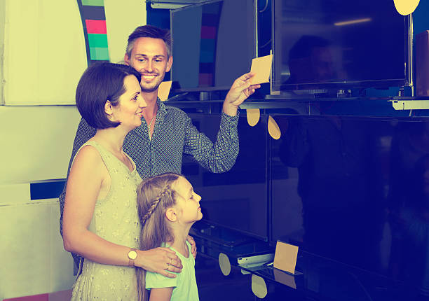 istock parents with daughter choosing new big TV screen 629230088
