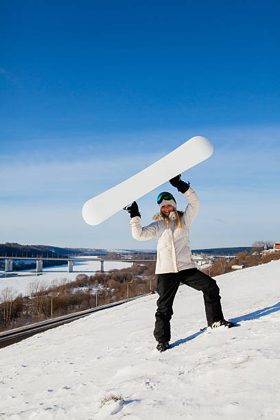 young woman showing her snowboard as a white empty space - outdoor pursuit fotos imagens e fotografias de stock