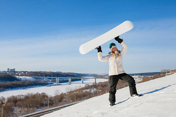 young woman showing her snowboard as a white empty space - outdoor pursuit fotos imagens e fotografias de stock