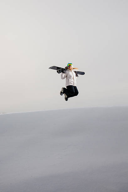 istock Young woman jumping with her snowboard 629238048