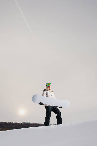 young woman showing her snowboard as a white empty space - outdoor pursuit fotos imagens e fotografias de stock