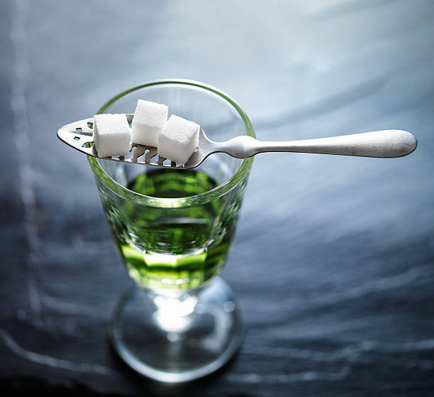 glass of absinthe absinthe in pontarlier glass with spoon and sugar cubes absinthe spoon stock pictures, royalty-free photos & images