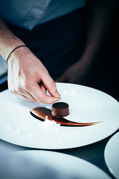 Chef putting a green leaf on chocolate dessert